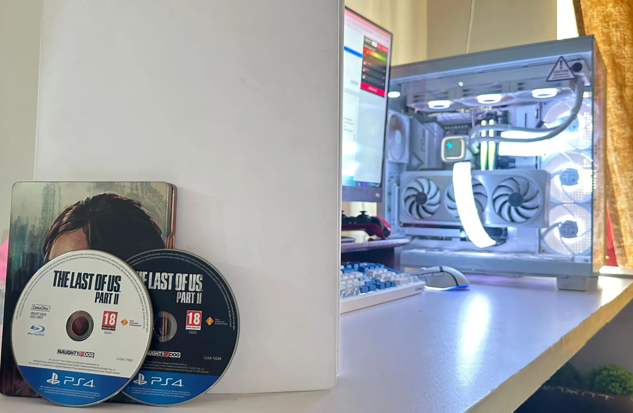 Hai đĩa game The Last of Us Part II bên cạnh PC và PS5, thể hiện kích thước game ngày càng lớn.