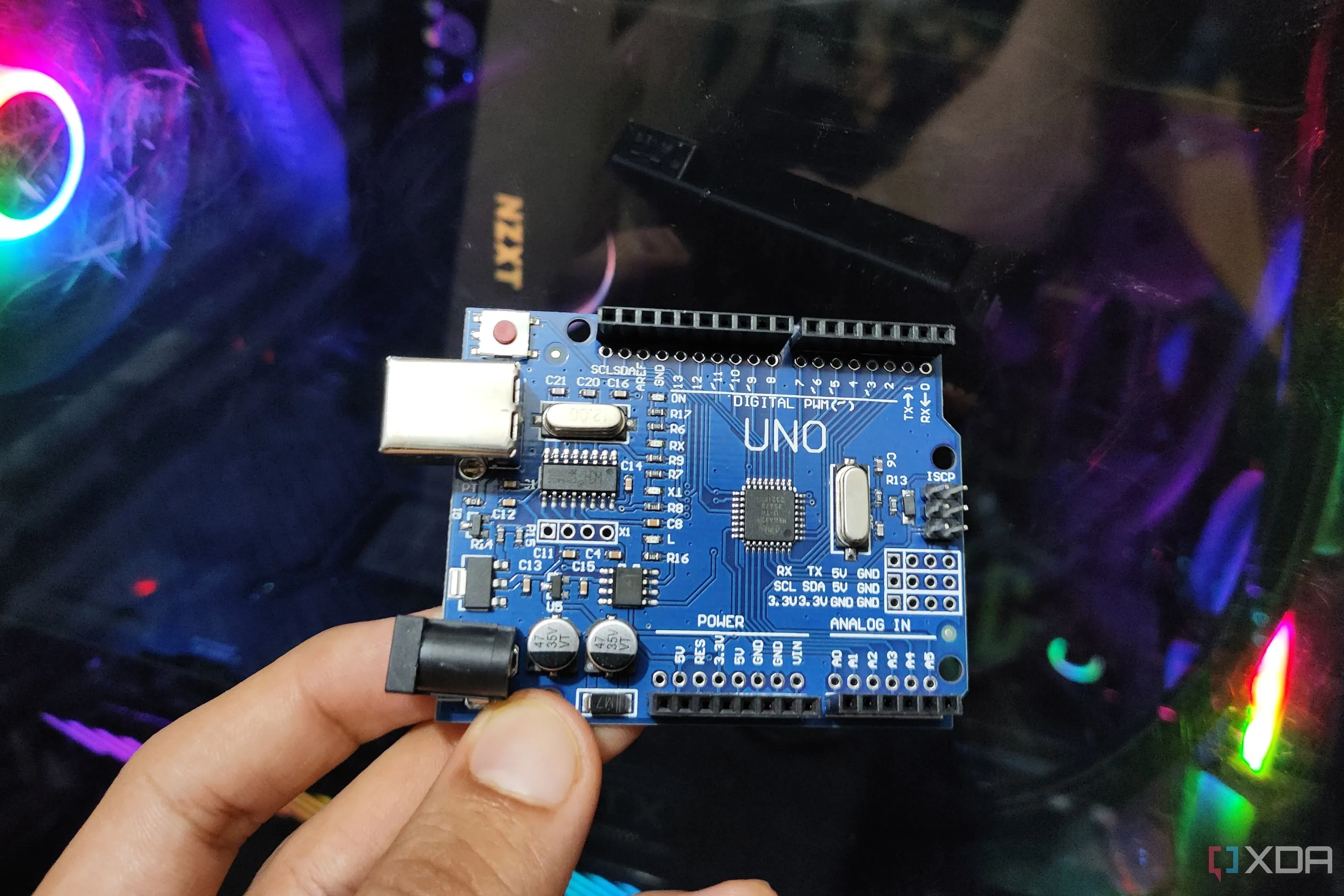 Hình ảnh một người đang cầm bo mạch Arduino Uno trong tay, thể hiện tính ứng dụng thực tế và khả năng di động của vi điều khiển này.