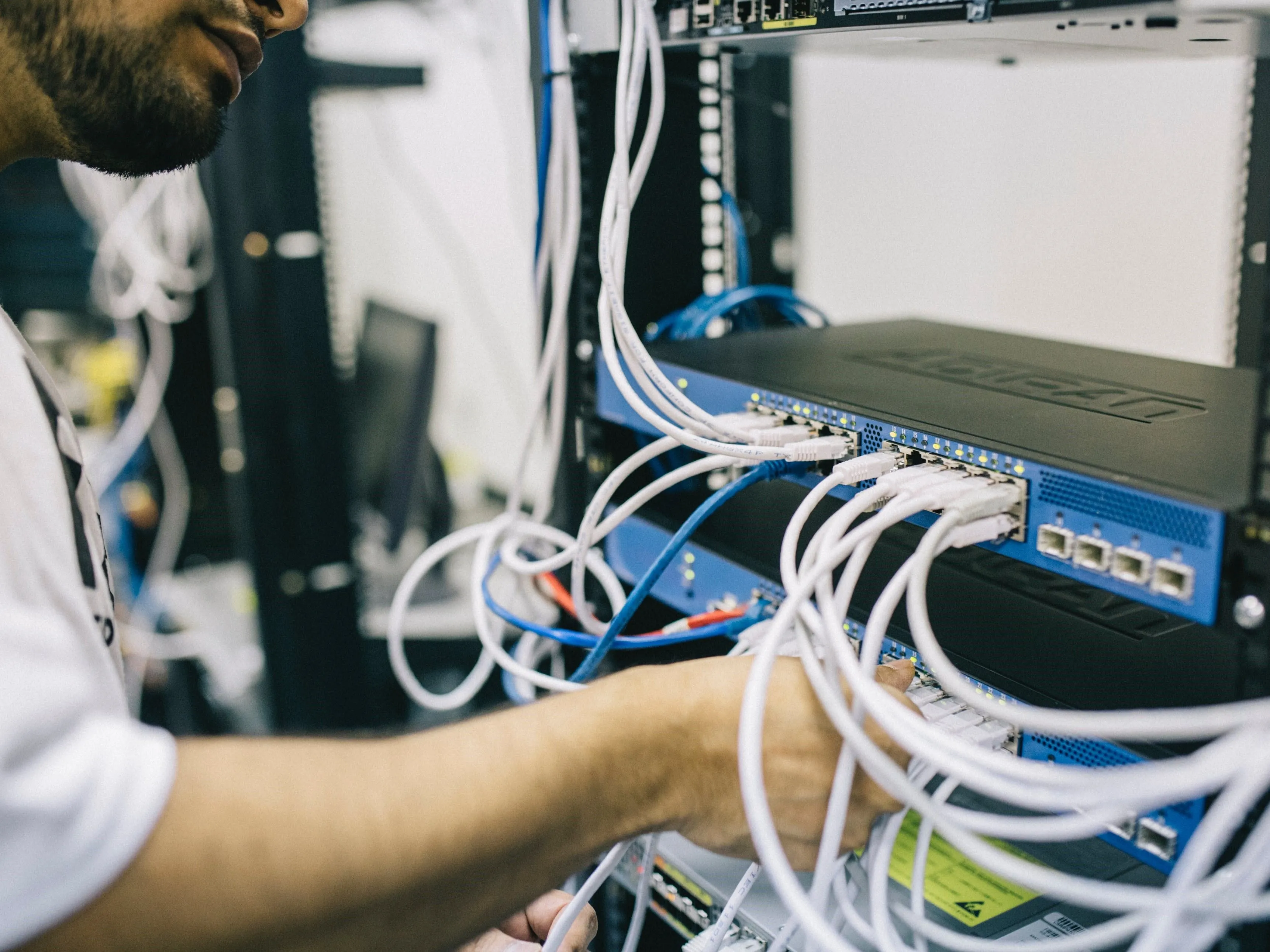 Kỹ sư đang cắm cáp Ethernet vào thiết bị chuyển mạch trong môi trường công nghiệp