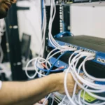 Kỹ sư mạng đang cắm cáp Ethernet vào bộ chuyển mạch để cấu hình hệ thống