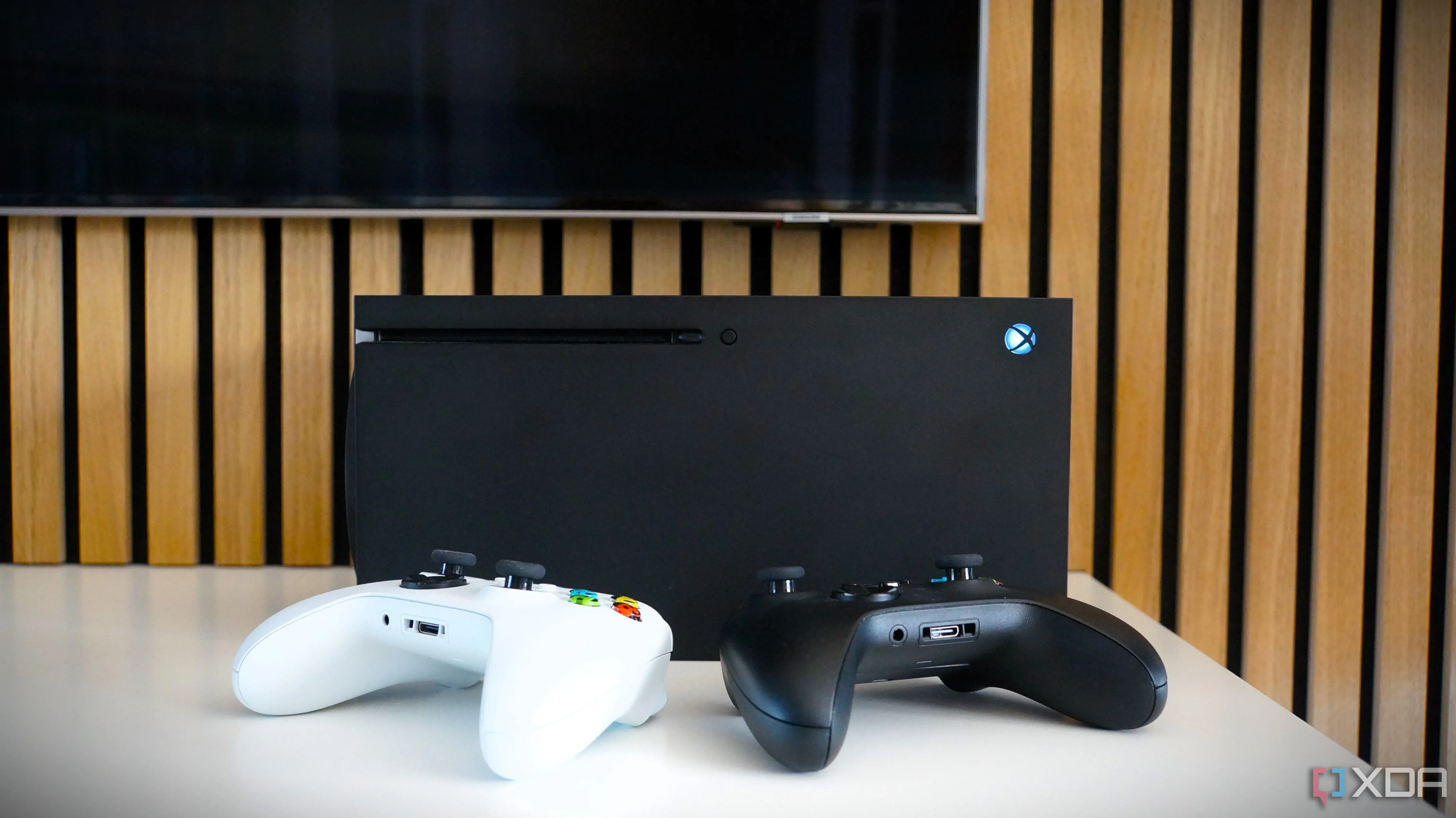 Máy chơi game Xbox Series X cùng tay cầm điều khiển trước màn hình Samsung, biểu tượng cho quyền tự sửa chữa và nâng cấp console.