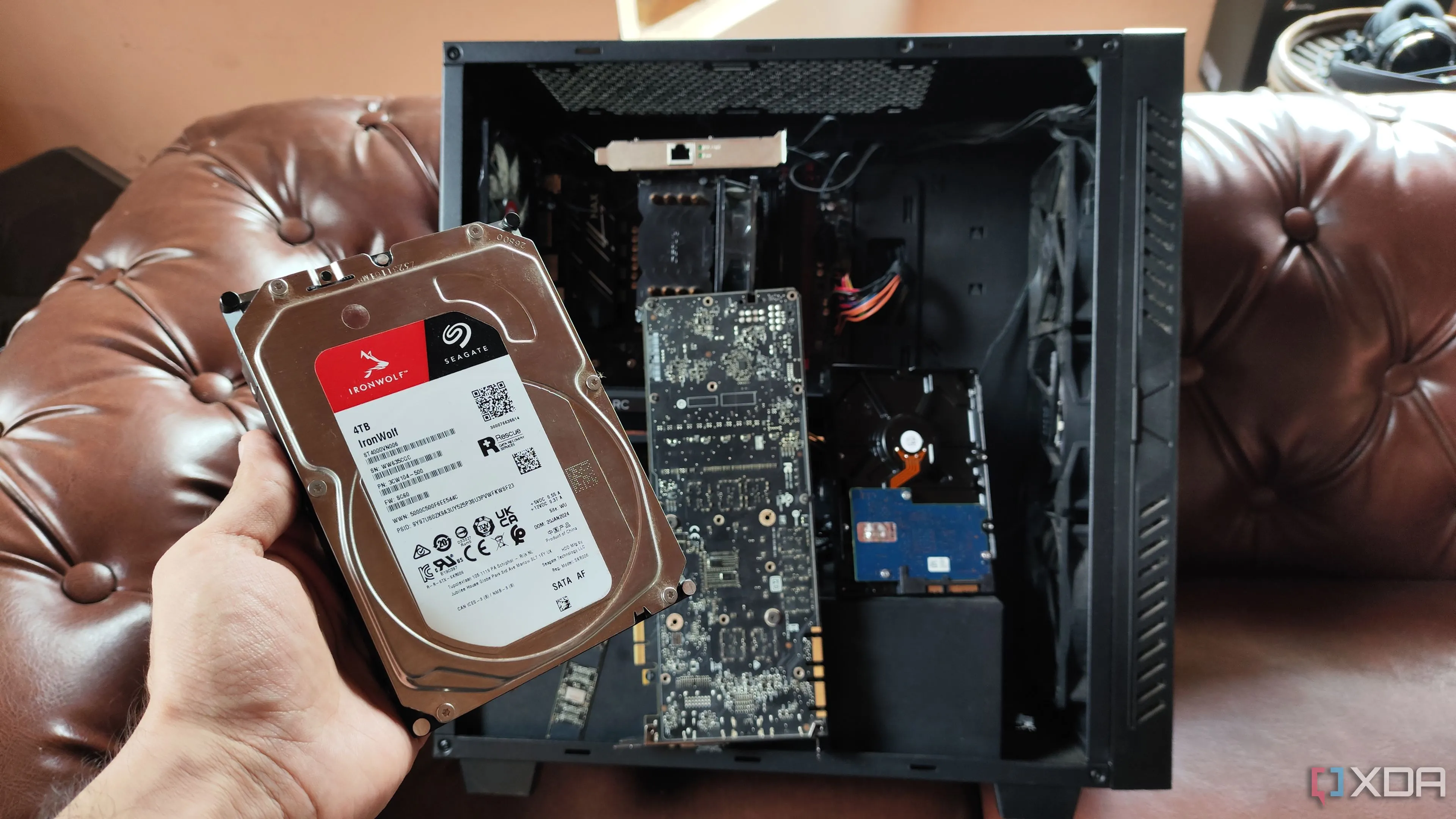 Một người đang cầm ổ HDD trước một hệ thống NAS tự xây dựng