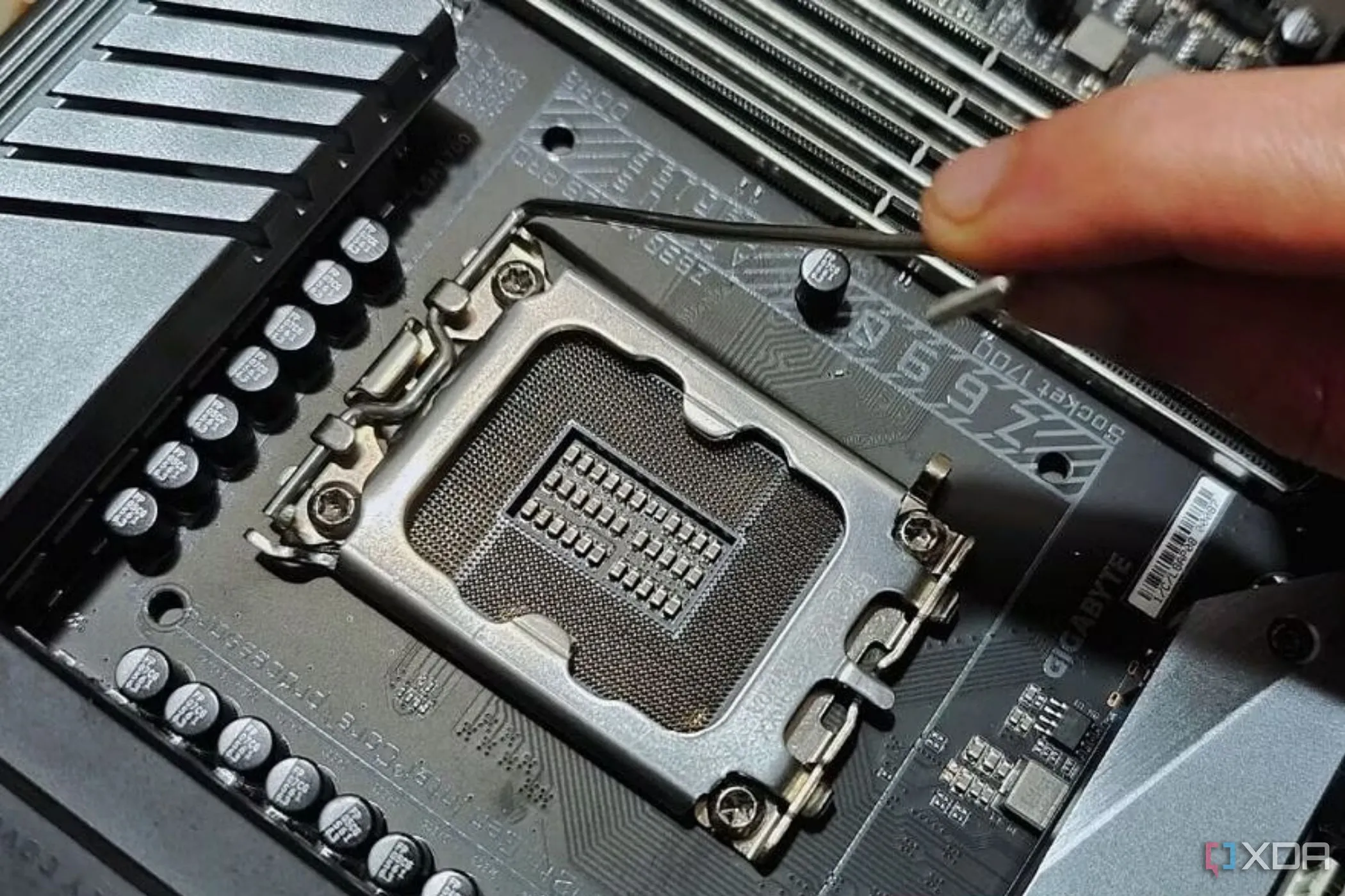 Một người đang giữ cần gạt kim loại gần socket CPU trên bo mạch chủ