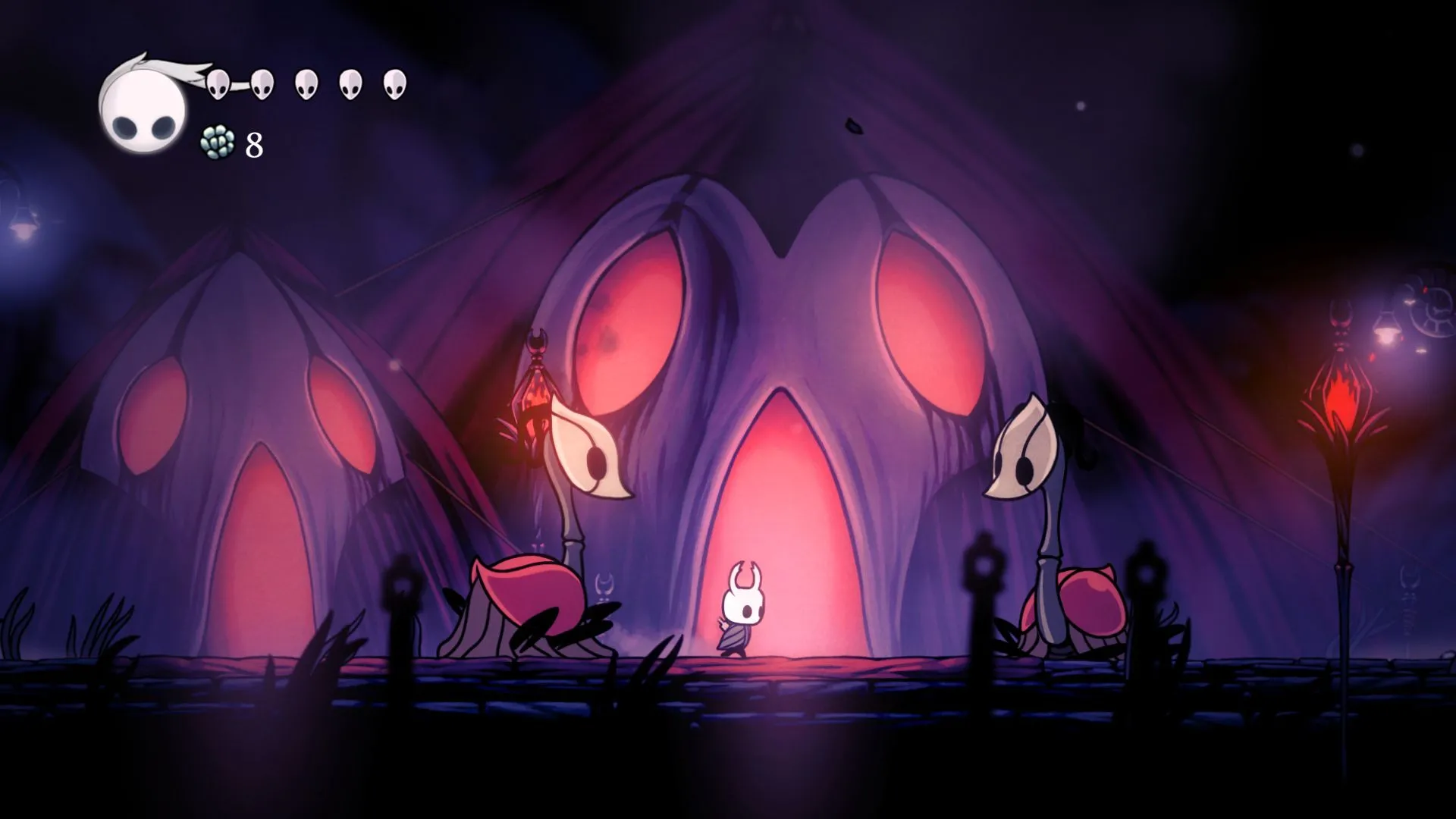 Nhân vật hiệp sĩ trong game Hollow Knight đứng giữa hai sinh vật, minh họa đồ họa độc đáo của tựa game phiêu lưu kinh điển.