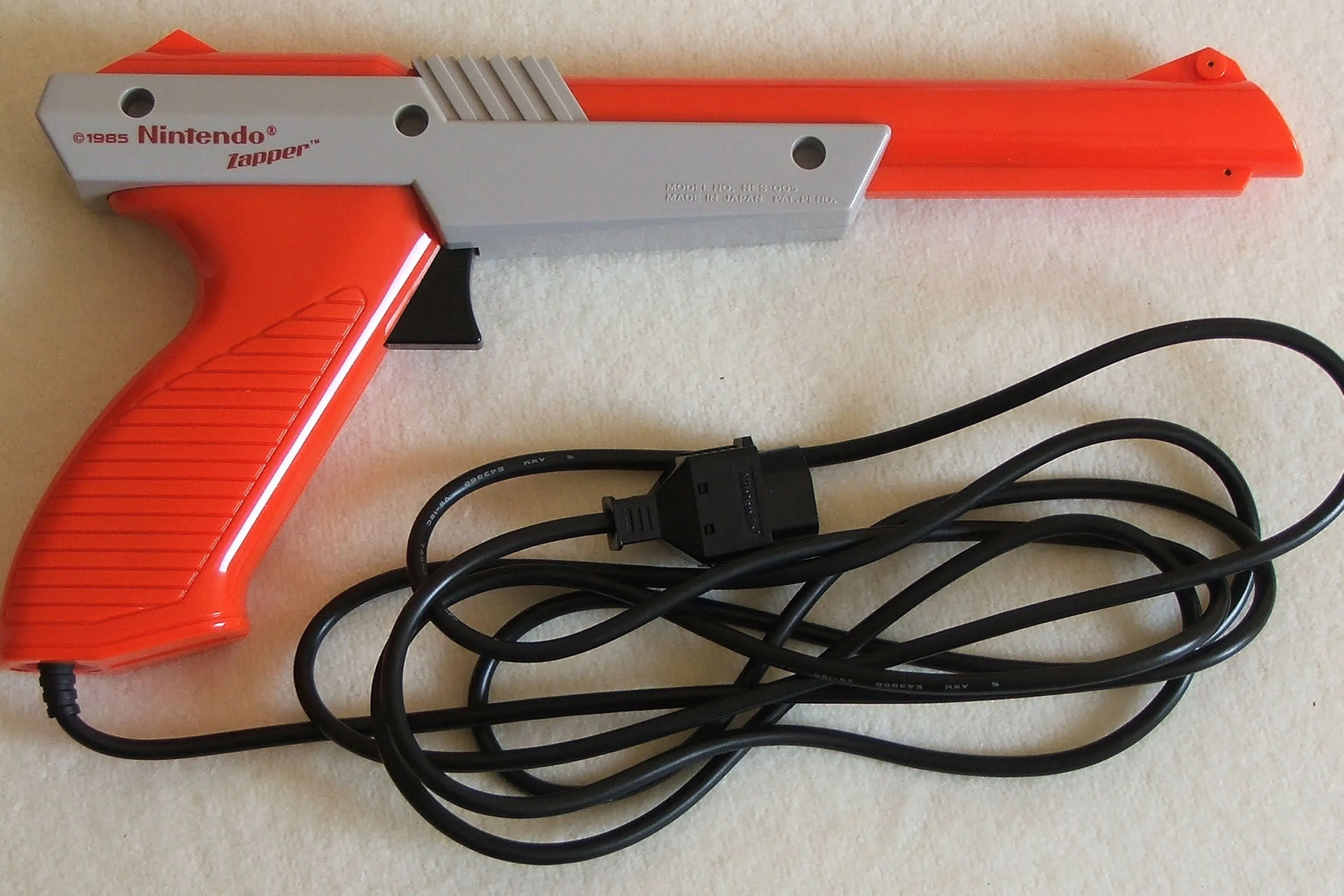 Súng NES Zapper màu xám kinh điển trên sàn nhà, phụ kiện huyền thoại của game Duck Hunt